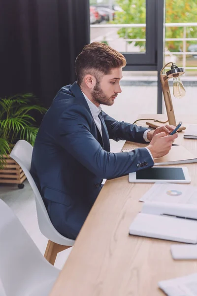 Giovane uomo d'affari che utilizza smartphone vicino al tablet digitale in sala riunioni — Foto stock