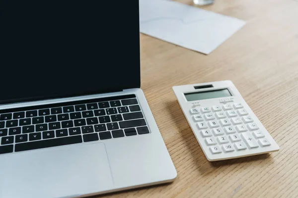 Computer portatile con schermo bianco e calcolatrice su tavolo di legno — Foto stock