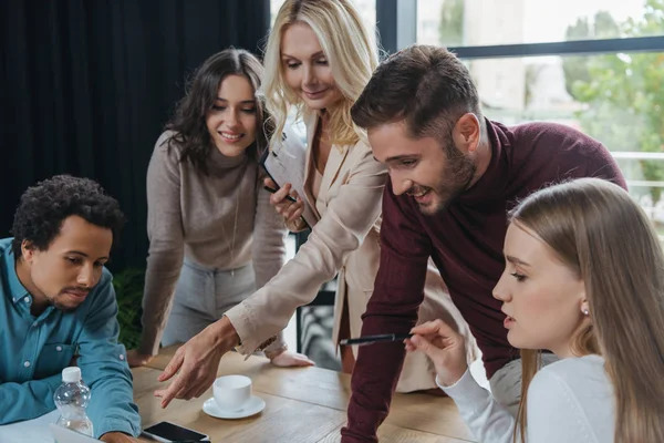 Mulher de negócios madura apontando com o dedo durante reunião de negócios com jovens colegas multiculturais — Stock Photo