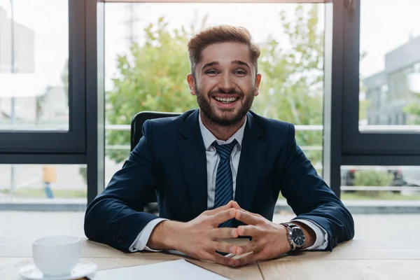 Fröhlicher Geschäftsmann lächelt in die Kamera, während er im Besprechungsraum sitzt — Stockfoto