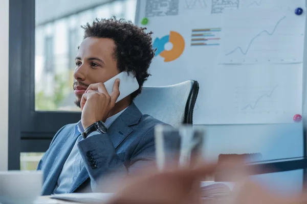Enfoque selectivo del joven empresario afroamericano hablando en el teléfono inteligente en la oficina - foto de stock