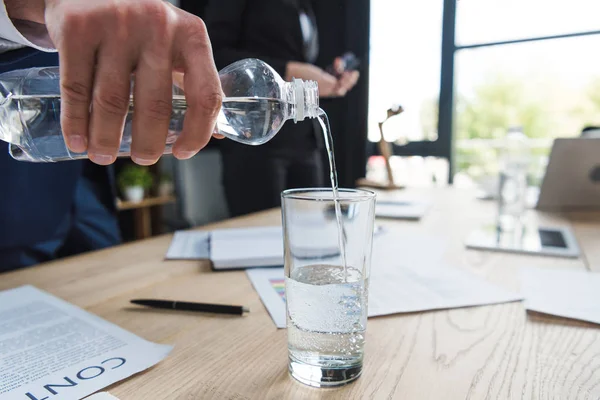 Vista ritagliata di uomo d'affari versando acqua in vetro — Foto stock