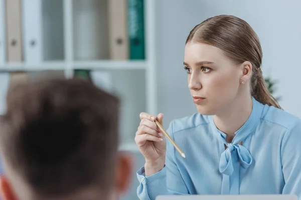 Selektiver Fokus der aufmerksamen Geschäftsfrau, die Kollegen zuhört und bei Geschäftstreffen Bleistift hält — Stockfoto