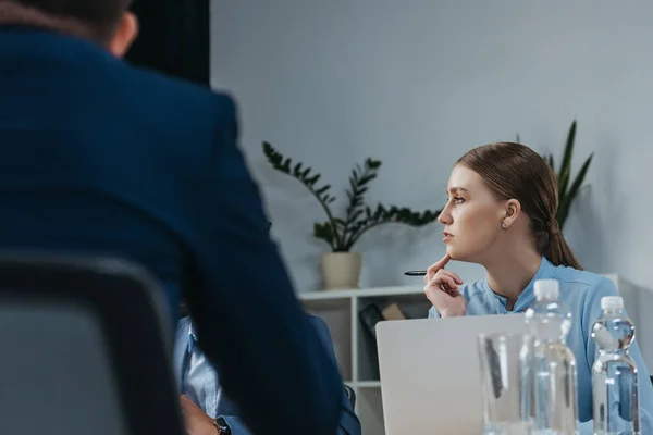 Atenta mujer de negocios escuchando a sus colegas durante la reunión de negocios en la oficina - foto de stock