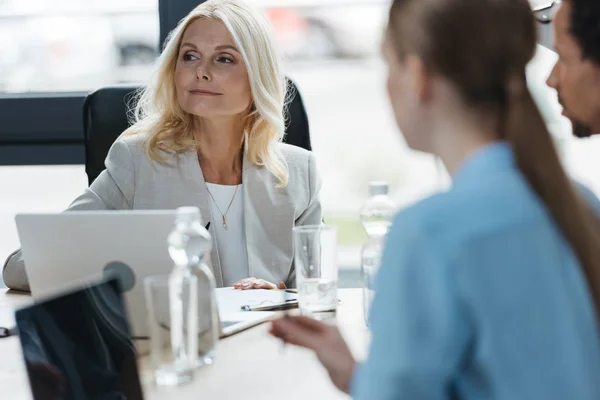 Selective focus of confident businesswoman at business meeting with young multicultural colleagues — Stock Photo