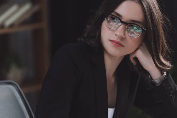 Réfléchie, jeune femme d'affaires dans des lunettes regardant loin dans le bureau — Photo de stock