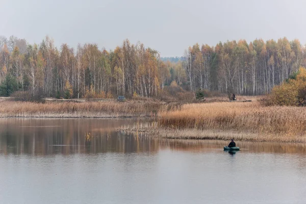 Львов, Украина - 23 октября 2019 года: вид сзади рыбака, держащего удочку, сидящего на лодке и рыбачащего в озере — стоковое фото