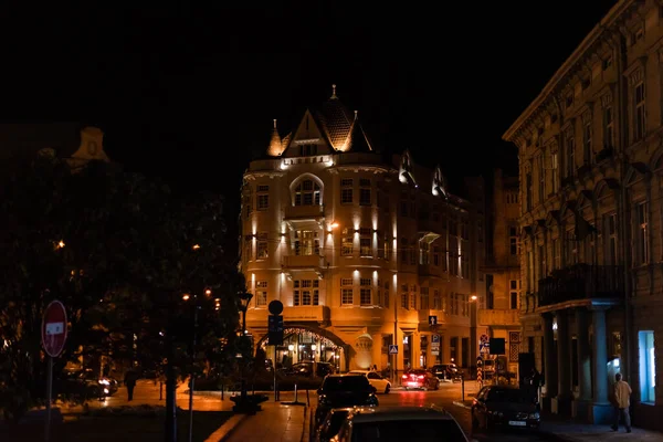 LVIV, UKRAINE - 23. OKTOBER 2019: Gebäude mit Beleuchtung in der Nähe von Straßen mit Autos in der Nacht — Stockfoto
