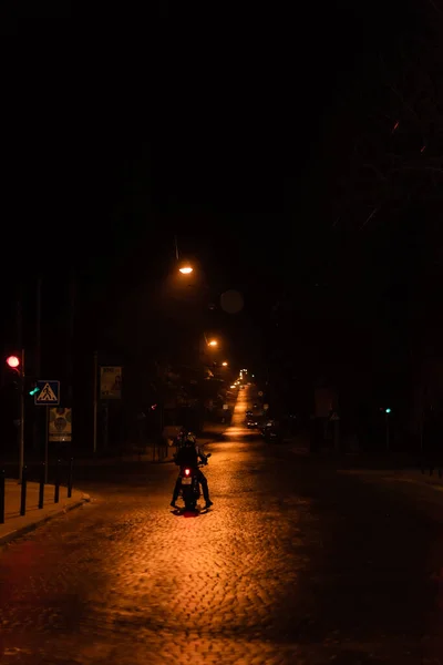 LVIV, UKRAINE - OCTOBER 23, 2019: silhouette of man in helmet riding scooter on street at night — Stock Photo