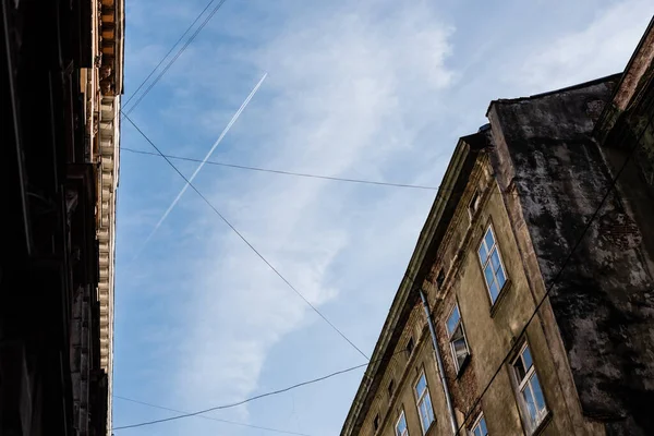 Vista de ángulo bajo de edificios antiguos y cables eléctricos contra el cielo azul en lviv, Ucrania - foto de stock