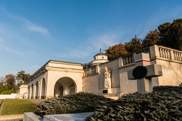 Pulido tumba con cruz cerca de galería de arco con la escultura en el cementerio de lychakiv en Lviv, Ucrania - foto de stock