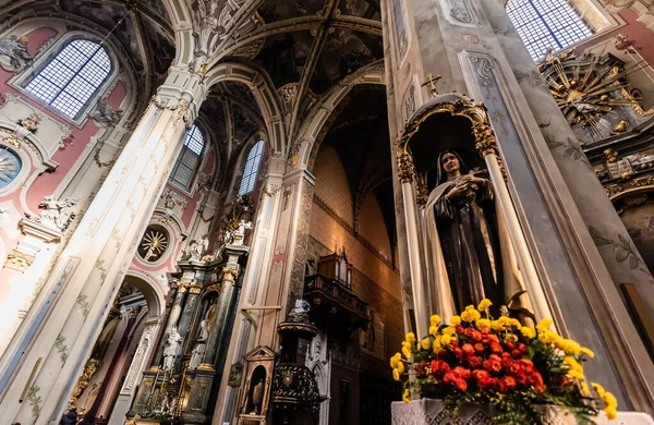 LVIV, UCRANIA - 23 DE OCTUBRE DE 2019: interior de la catedral latina lviv con flores amarillas cerca de la escultura femenina - foto de stock