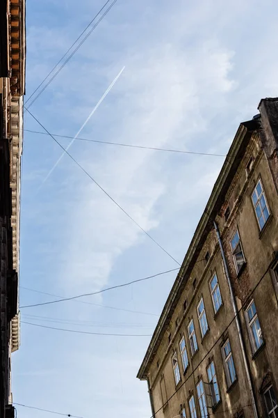 Vista de ángulo bajo de casas antiguas y cables eléctricos contra el cielo azul en lviv, Ucrania - foto de stock