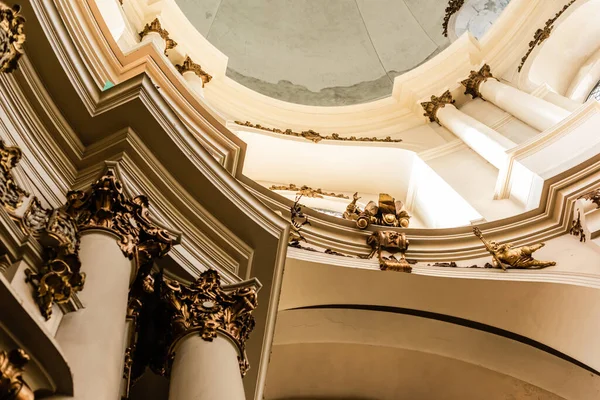 LVIV, UCRANIA - 23 DE OCTUBRE DE 2019: vista de ángulo bajo de columnas decoradas con elementos dorados en la iglesia dominicana - foto de stock