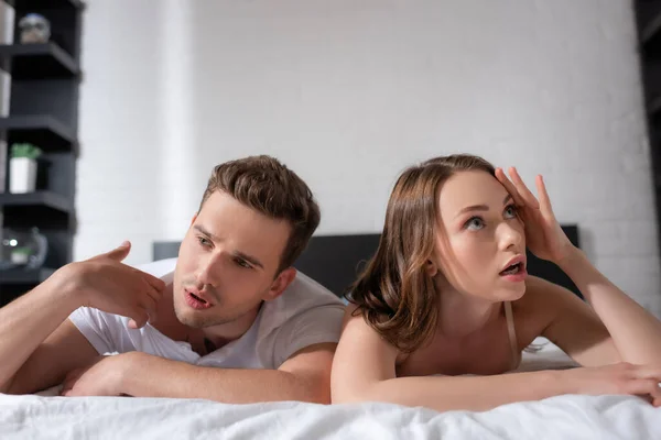 Displeased couple lying on bed and feeling hot — Stock Photo