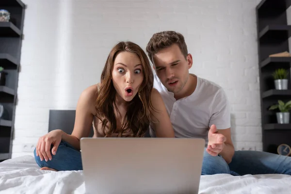 Überraschtes Paar schaut Film auf Laptop im Schlafzimmer — Stockfoto