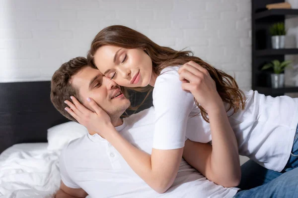 Feliz jovem mulher com olhos fechados abraçando homem feliz no quarto — Fotografia de Stock