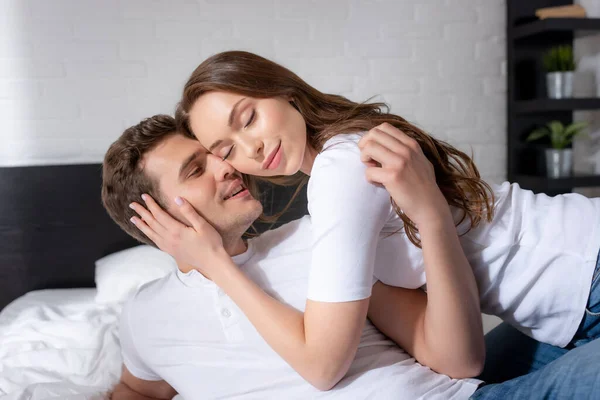 Heureux jeune femme avec les yeux fermés étreignant homme heureux dans la chambre — Photo de stock