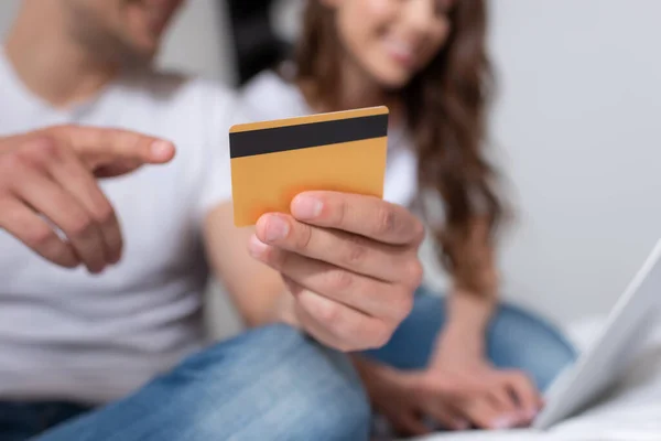 Обрізаний вид чоловіка, який вказує пальцем на кредитну картку біля жінки вдома — стокове фото