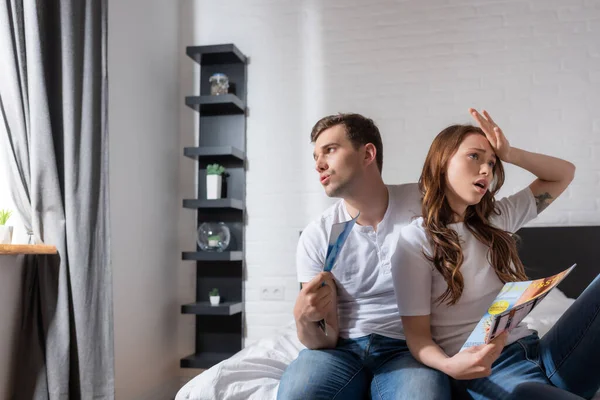 Unzufriedenes Paar hält Magazine in der Hand, während es sich im Schlafzimmer heiß fühlt — Stockfoto