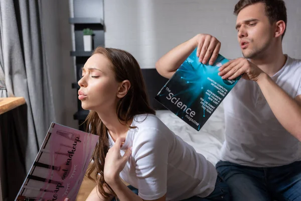 Handsome man holding magazine near displeased girl feeling hot at home — Stock Photo