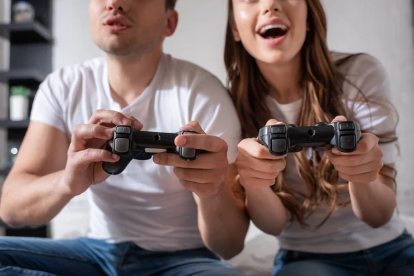 KYIV, UKRAINE - MAY 15, 2020: cropped view of excited woman and displeased man playing video game in bedroom — Stock Photo