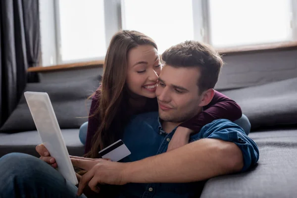 Fröhliche Frau lächelt neben Mann mit Kreditkarte neben digitalem Tablet beim Online-Shopping — Stockfoto