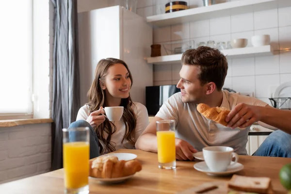 Selective focus of cheerful couple looking at each other near delicious breakfast on table — Stock Photo