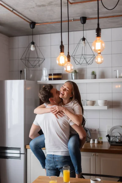 Селективное внимание мужчины целующегося и держащегося в руках веселой девушки — стоковое фото