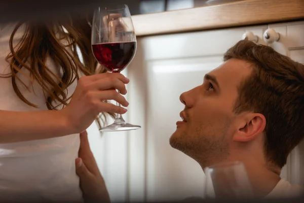 Woman holding glass of red wine near handsome man — Stock Photo