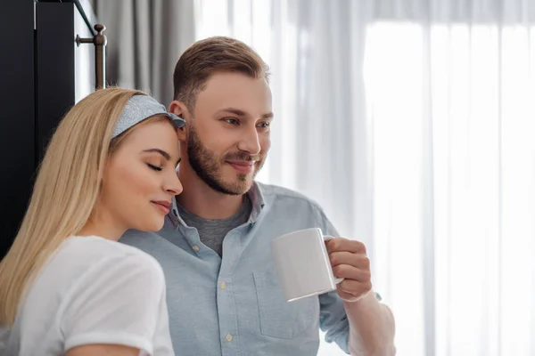 Fille heureuse avec les yeux fermés debout avec petit ami heureux tenant tasse de café — Photo de stock