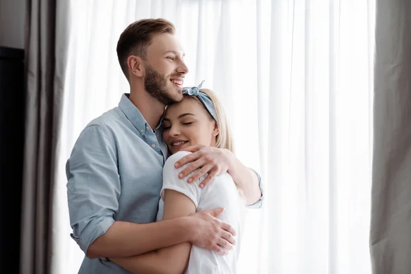 Feliz hombre abrazando alegre chica en casa - foto de stock