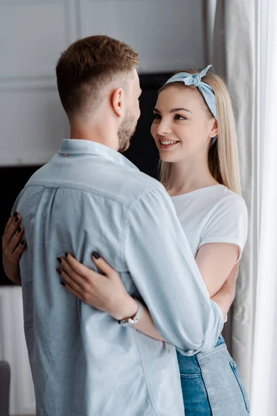 Alegre mujer abrazando barbudo novio en casa - foto de stock