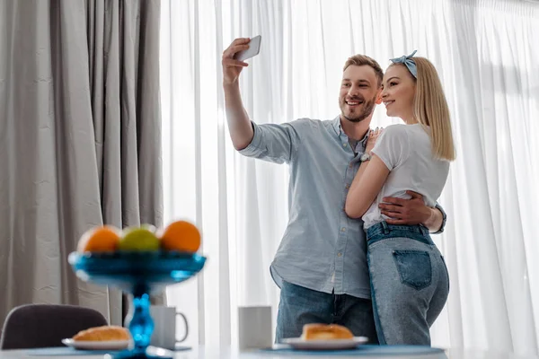 Selective focus of man taking selfie with cheerful girl near breakfast — Stock Photo