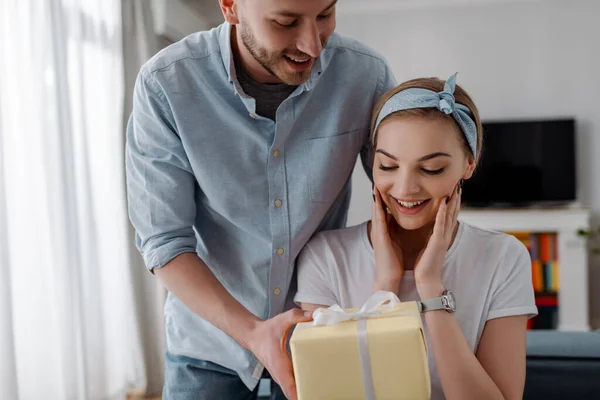 Menina feliz olhando para o presente perto bonito namorado — Fotografia de Stock