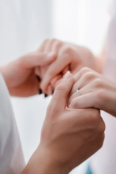 Vista recortada de la mujer con anillo de compromiso en el dedo cogido de la mano con el hombre - foto de stock