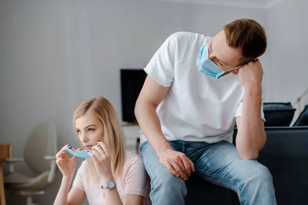 Uomo in maschera medica seduto vicino fidanzata attraente — Foto stock