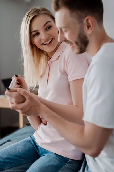 Selective focus of happy girl holding pregnancy test with positive result near cheerful boyfriend — Stock Photo