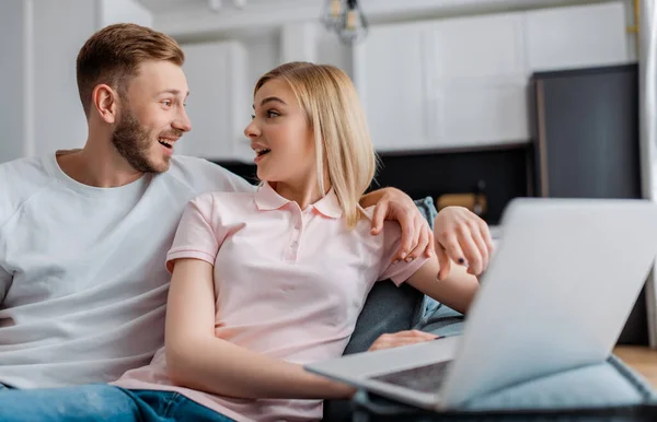 Selective focus of couple looking at each other near laptop — Stock Photo