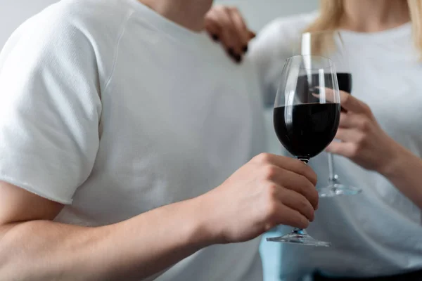 Cropped view of man and woman holding glasses with red wine — Stock Photo