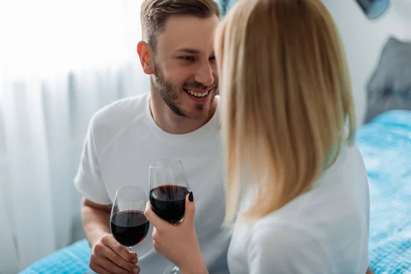 Messa a fuoco selettiva di felice uomo e donna che tiene i calici con vino rosso — Foto stock