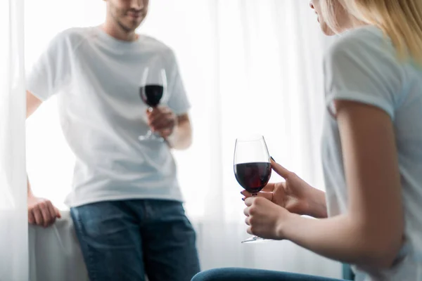Vista cortada de homem e mulher segurando copos com vinho tinto em casa — Fotografia de Stock