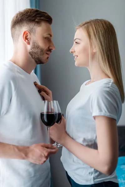 Side view of happy man and woman holding glasses with red wine — Stock Photo
