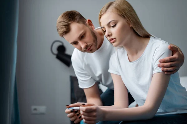 Homme triste et frustré petite amie regardant test de grossesse à la maison — Photo de stock