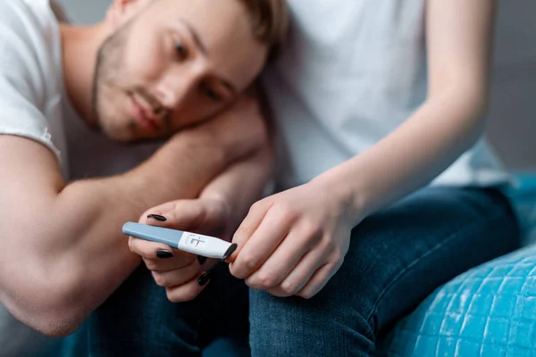 Selective focus of pregnancy test with negative result in hands on woman near upset man — Stock Photo