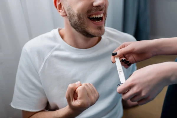 Cropped view of girl holding pregnancy test with positive result near happy man — Stock Photo