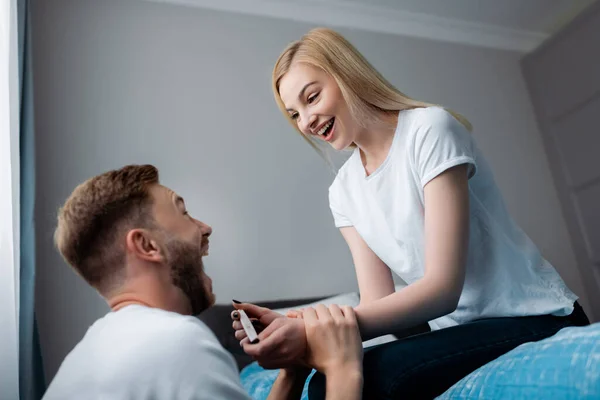 Happy young woman holding pregnancy test with positive result near excited man — Stock Photo