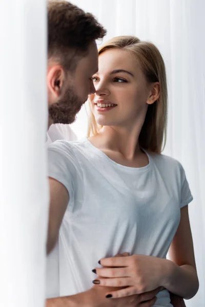 Barbudo homem abraçando alegre mulher em casa — Fotografia de Stock