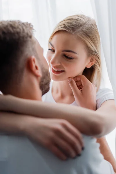 Selektiver Fokus des Mannes berührt Gesicht einer lächelnden jungen Frau — Stockfoto