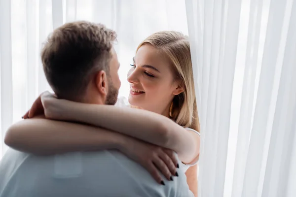 Selective focus of smiling woman embracing and looking at boyfriend — Stock Photo